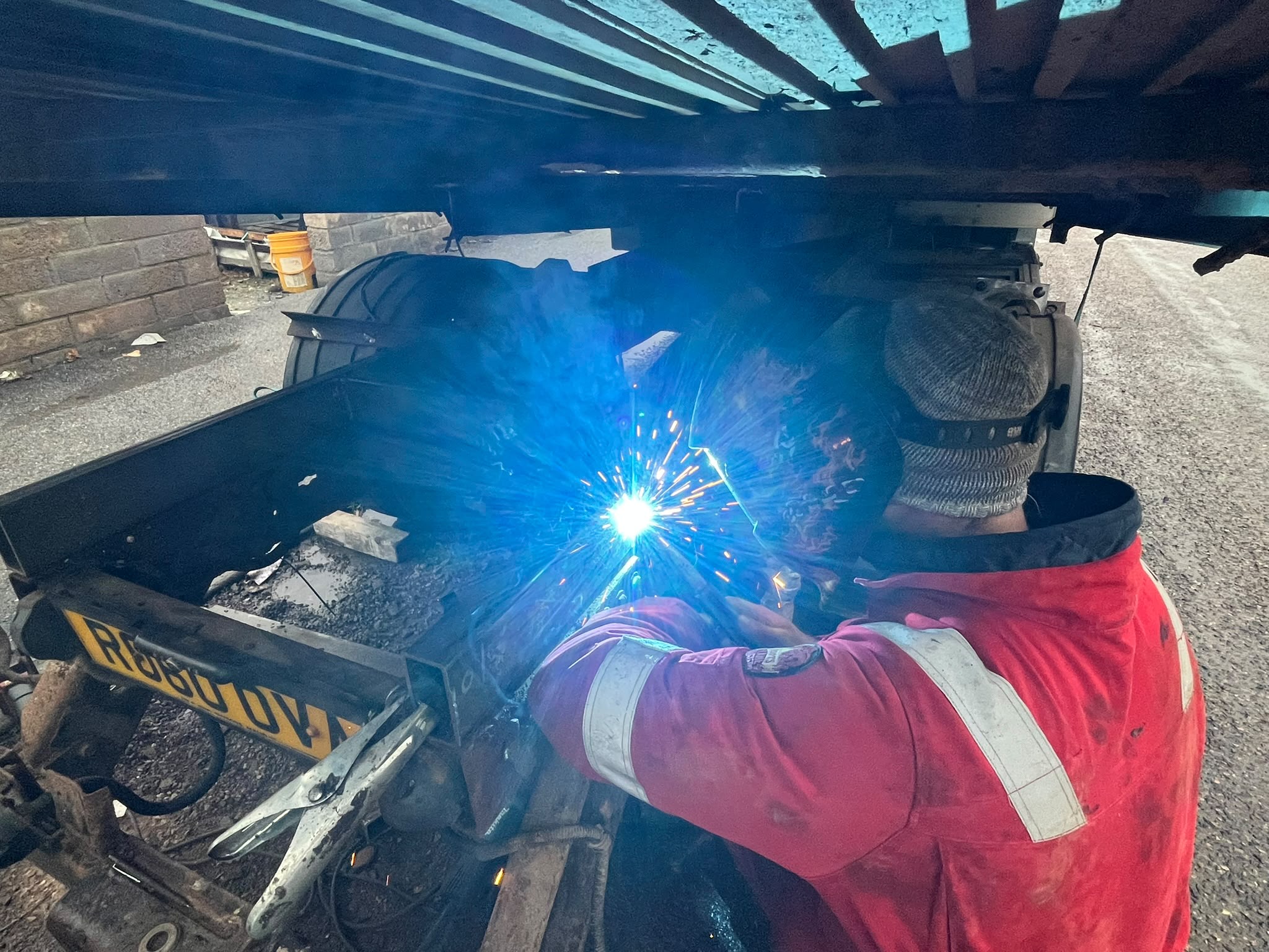 Mobile welder repairing corrosion underneath a vehicle
